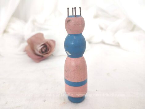 Voici un adorable ancien tricotin en bois, au clous posés de façon artisanale et peint à la main rose et bleu pastel avec une forme très simplifiée au visage effacé.