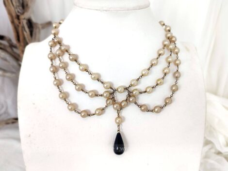 Voici un collier original avec des perles nacrées sur une composition forme princesse sur 3 rangs et une perle goutte noire au centre.
