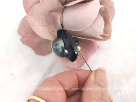 Voici une épingle à chapeaux fibule décorée d'une forme ronde en bakélite aux contours géométriques avec au centre un perle en métal et son petit embout.