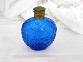 Datant des années 80, voici un ancien petit flacon en verre bleu décoré de reliefs avec son bouchon en laiton et signé sous le socle du parfumeur Ulrich de Varens.