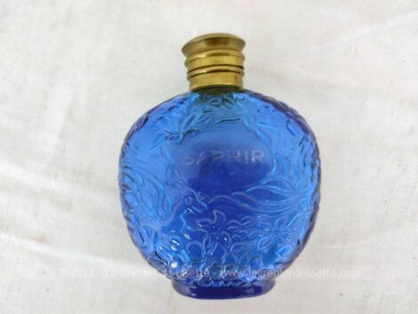 Datant des années 80, voici un ancien petit flacon en verre bleu décoré de reliefs avec son bouchon en laiton et signé sous le socle du parfumeur Ulrich de Varens.