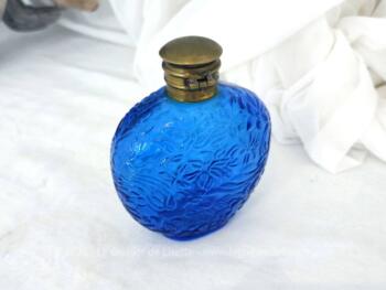 Datant des années 80, voici un ancien petit flacon en verre bleu décoré de reliefs avec son bouchon en laiton et signé sous le socle du parfumeur Ulrich de Varens.