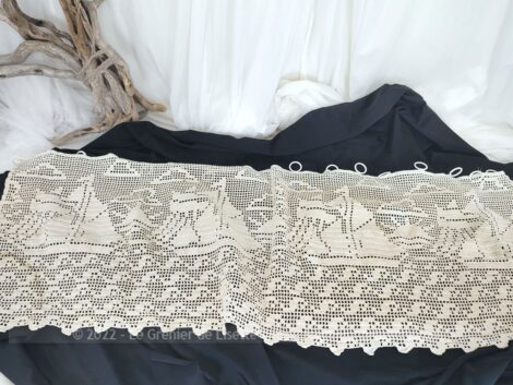 Fait main sur 110 x 42 cm, voici un ancien rideau réalisé au crochet en fil de coton bistre avec des dessins de bateaux voguant sur l'eau.