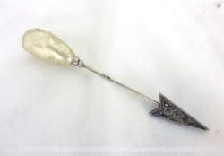 Voici une épingle à chapeaux fibule décorée d'une perle de verre nacrée et son embout en métal argenté en forme de flèche.