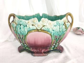 Ancienne belle jardinière en barbotine décorée par des fleurs de seringa et leur feuillage, sur fond fuchsia et vert d'au. Pièce numérotée et signée.