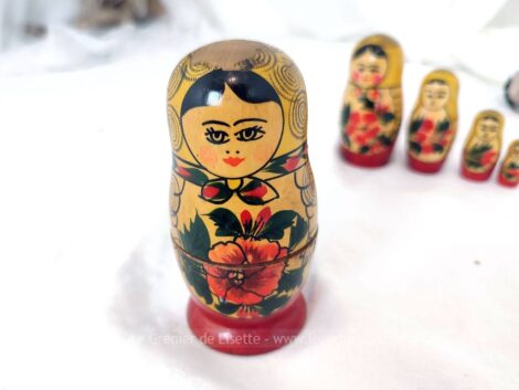 Voici un ancien jeu de 5 poupées Russes au châle jaune tenant un hibiscus dans les bras.