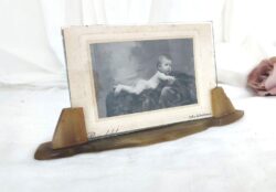 Voici un ancien porte-photo en bakélite avec son verre et sa photo d'un beau bébé nu assis sur son coussin. Pièce unique.