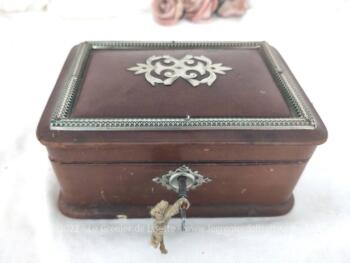 Voici un ancienne boite en bois habillée de cuir avec décors en métal argenté , intérieur capitonné en satin rouge, et verrou avec clé.