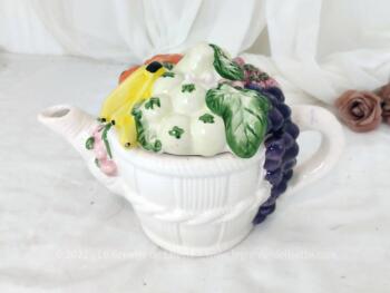 Voici une théière ou cafetière originale, en faïence blanche en forme de panier en osier rempli de fruits colorés qui forment le couvercle.