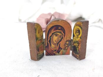 Voici un triptyque en bois ouvragé, portable avec une fois ouvert le dessin de la Vierge portant l'enfant Jésus et sur chacune des portes latérales un Archange. Dans le style des artisans grecs.