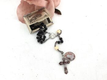 Proposé dans une petite boite en métal gravé à la main, voici un ancien petit chapelet aux mini perles en verre noires avec croix et médailles en fer.