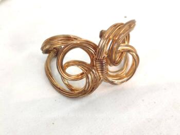 Large et beau bracelet en métal doré composé de fils tressés formant des noeuds. Très bien ouvragé avec juste une petite ouverture pour faire  passer le poignet, pas trop large. Vraiment original !