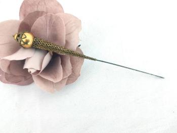 Voici une superbe épingle à chapeaux décorée d'un cône en métal doré ciselé surmonté d'une perle dorée habillée de pétales, le tout sur 15 cm.