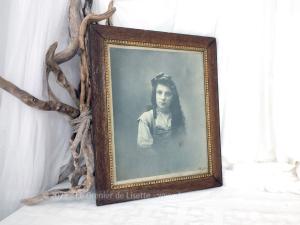 Sur 33 x 40 x 1.3 cm, voici un cadre en bois avec reliefs intérieurs dorés pour mettre en valeur une photo d'une jeune fille avec un noeud dans ses longs cheveux. A susprendre.