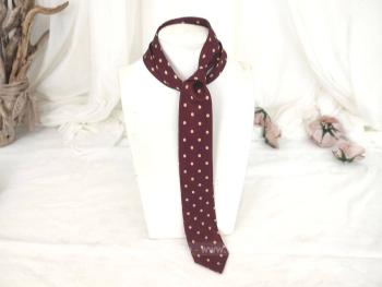 Voici une ancienne cravate vintage bordeaux pois écrus en polyester.  Pour homme ou femme !
