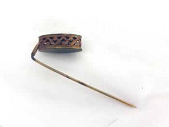 Ancienne épingle à chapeaux de 7 cm de long composée d'un décor en laiton formant un tambourin ovale habillé par un tressage pour la décorer comme un bijoux.