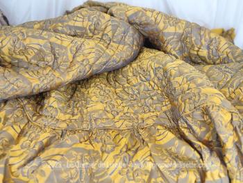 Sur 145 x 220 cm + 38 cm de volant de chaque coté, voici un ancien couvre lit matelassé des années 70/80 en tissus satiné sur fond jaune doré aux dessins bleu gris d'un coté et jaune safran l'autre. 
