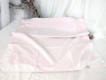 Voici une taie d'oreiller rose bien originale avec ses incrustations de tissus blanc sur deux angles et ses broderies de fleurs.