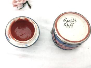 Datant des années 70, voici une ancienne boite marocaine ronde en céramique rose et bleue, habillée par de superbes décors en étain pour un effet shabby. Fait main, elle est estampillée "Safi" et du nom de son créateur.