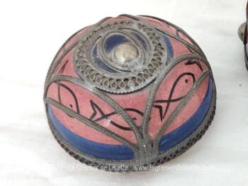 Datant des années 70, voici une ancienne boite marocaine ronde en céramique rose et bleue, habillée par de superbes décors en étain pour un effet shabby. Fait main, elle est estampillée "Safi" et du nom de son créateur.