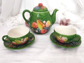 Sur fond vert menthe, voici une théière ou cafetière originale, en barbotine polychrome décorée de fruits avec 2 grandes tasses et soucoupes assorties.