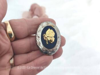 Top vintage, voici une boucle de foulard ou de revers de col représentant un papillon doré en relief sur fond noir au pourtour en métal ouvragé représentant une guirlande de fleurs.