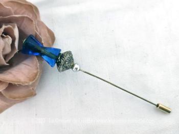 Voici une épingle à chapeaux fibule avec en décoration une composition  réalisée avec une grande perle de verre bleu en forme de double cône et une perle en métal ciselé, qui se termine par un petit embout.