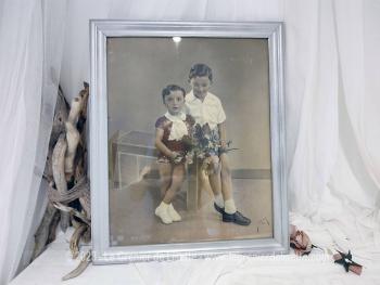 Sur 56.5 x 46.5 x 2 cm, voici un cadre en bois, peint couleur vieil argent  mettant en valeur une photos représentant deux garçonnets et signée par le photographe. Tout dans ce cadre nous transporte avec nostalgie dans le monde vintage des années 50!