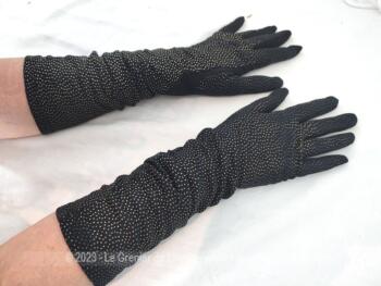 Voici une paire vintage de longs gants noirs en tissus élastiqué noir et recouvert de très petits pois dorés en relief pour une tenue habillée remplie d’élégance ! Made in France.