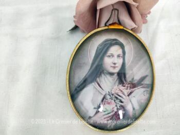 Petit cadre bombé à l'effigie de Sainte Thérèse composé d'une vitre en plastique et d'un contour en laiton.