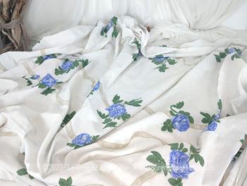 Sur 135 x 205 cm, voici un beau coupon tissus ou nappe en coton fond blanc habillé par des rubans écrus sur lequel des roses bleues forment une guirlande