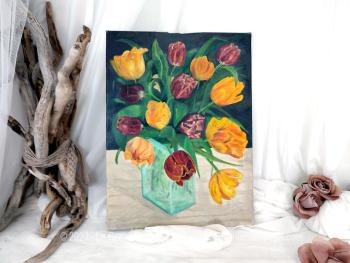 Sur 30 x 10cm, voici un tableau éclatant d'une peinture à l'huile signée représentant un grand bouquet de tulipes à dominantes bordeaux et jaune orangé dans un vase en verre.