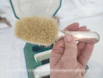 Voici un ancien coffret contenant un nécessaire de toilette en métal argenté comprenant une brosse à habits, un peigne, un pot à onguent, et une brosse à cheveux.