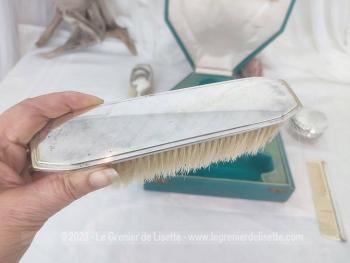 Voici un ancien coffret contenant un nécessaire de toilette en métal argenté comprenant une brosse à habits, un peigne, un pot à onguent, et une brosse à cheveux.