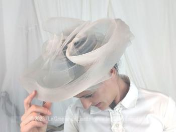 Voici un large chapeau bien orignal réalisé en sisal synthétique de couleur gris perle, avec un large rebord, noeuds et ruban pour un style très "British".