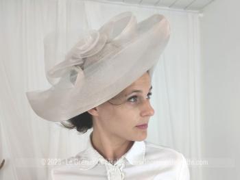 Voici un large chapeau bien orignal réalisé en sisal synthétique de couleur gris perle, avec un large rebord, noeuds et ruban pour un style très "British".