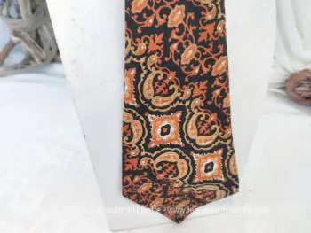 Voici une superbe cravate vintage seventeen, décorée de motifs d'arabesques psychédéliques dans les tons orangés et chocolat portant l'étiquette "Tergal et Fibre Polyester".