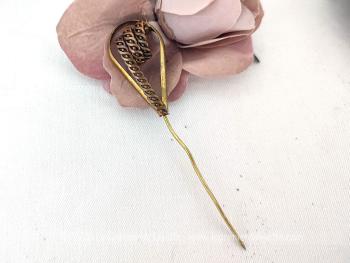Sur 10.5 cm de long,  voici une ancienne épingle à chapeaux en laiton avec un décor en forme de spirale ciselée inséré dans une arche fine pour la mettre en valeur comme un bijoux.