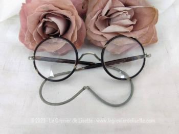 Avec des verres loupes, voici une ancienne paire de lunettes rondes au contour en bakélite imitation écaille de tortue avec des branches qui se terminent par un système à spirale flexible.