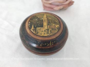 Sur 4.5 x 8,2 cm, voici une belle boite en bois tourné, petit vide poche ou bonbonnière, portant sur le couvercle la photo de la Basilique de Lourdes et sur le coté l'inscription "Lourdes".