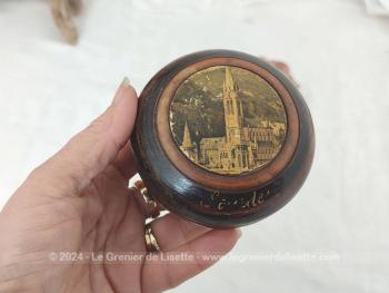 Sur 4.5 x 8,2 cm, voici une belle boite en bois tourné, petit vide poche ou bonbonnière, portant sur le couvercle la photo de la Basilique de Lourdes et sur le coté l'inscription "Lourdes".