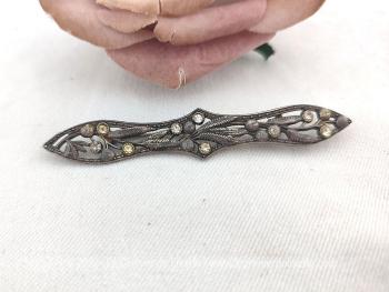Pour revers de veste, foulard ou cravate, voici une superbe, originale et vintage broche ou pince à cravate en métal argenté ciselé avec des formes de volutes et habillée de strass.