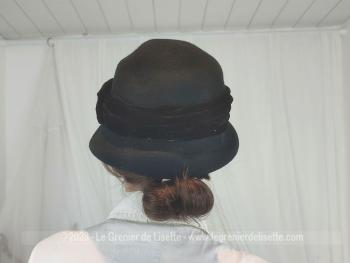 Superbe ancien chapeau cloche vintage en feutre noir décoré d'un large ruban et d'un noeud en velours noir et ses rebords asymétriques. Top look vintage !
