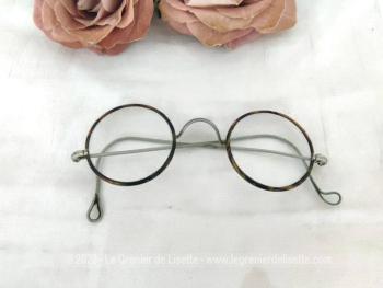 Voici une ancienne paire de lunettes rondes au contour en bakélite imitation écaille de tortue avec des branches qui se terminent par une boucle. Vraiment vintage !