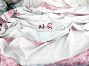 Sur 152 x 220 cm, voici une ancienne nappe damassée blanche avec des bandes rouges en décoration tout autour et  brodée au centre des monogrammes MG.