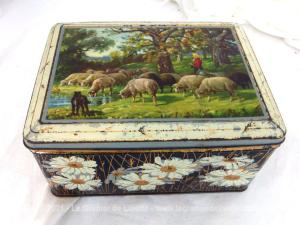 Voici un belle boite en métal vintage de 24 x 20 x 6.5 cm avec la sérigraphie sur le couvercle d'une scène d'une bergère avec ses moutons et des marguerites en relief sur les 4 autres faces.  