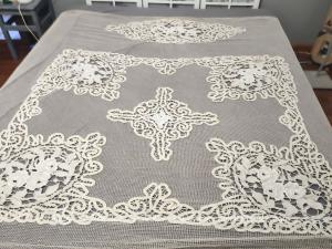 Voici un beau et ancien couvre lit en maille filet avec des décorations d'incrustation en dentelles Richelieu et des franges sur deux cotés.