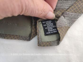 Voici une superbe cravate vintage seventeen de la marque Giorgio Armani décorée de motifs décoré gris et taupe avec renfort satiné au cou et doublure estampille Giorgio Armani.