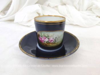 Estampillées " Limoges France", voici une belle tasse décorées à la main de bouquets de fleurs roses dans un écusson, le tout sur un fond bleu de Prusse lumineux et de liserés dorés, avec sa tasse assortie unie. Magnifique !