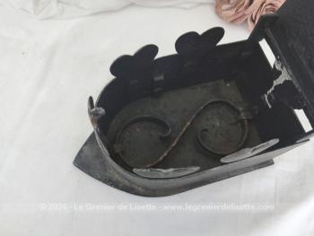 Voici un ancien fer à repasser en fonte patiné en noir avec réservoir à braises et décoré de coeurs muni d'un couvercle, de son systeme de fermeture et de son manche en bois.